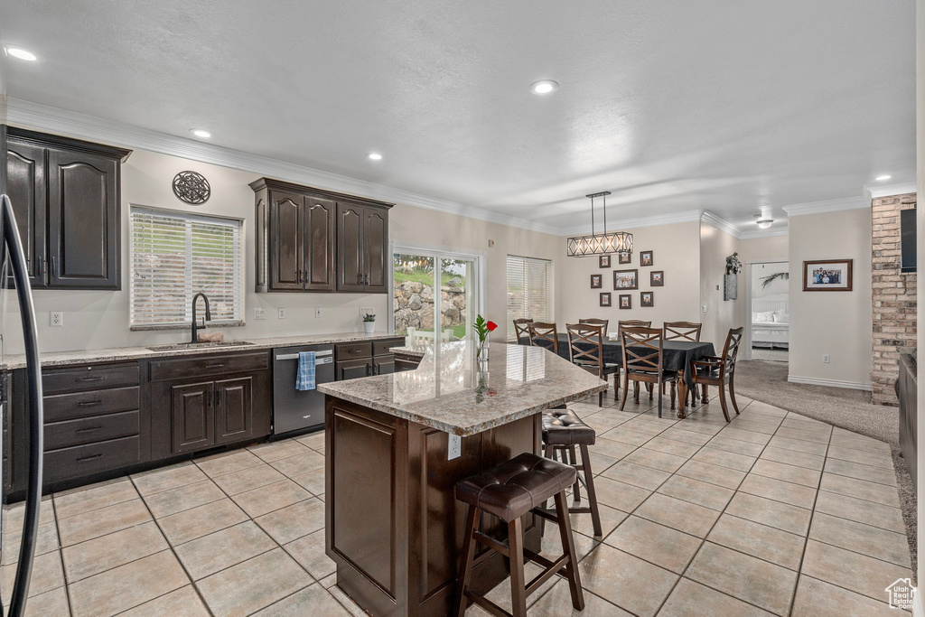 Kitchen featuring a sink, stainless steel dishwasher, a kitchen bar, a kitchen island, and light tile patterned floors