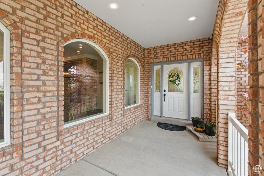 Doorway to property with brick siding and covered porch