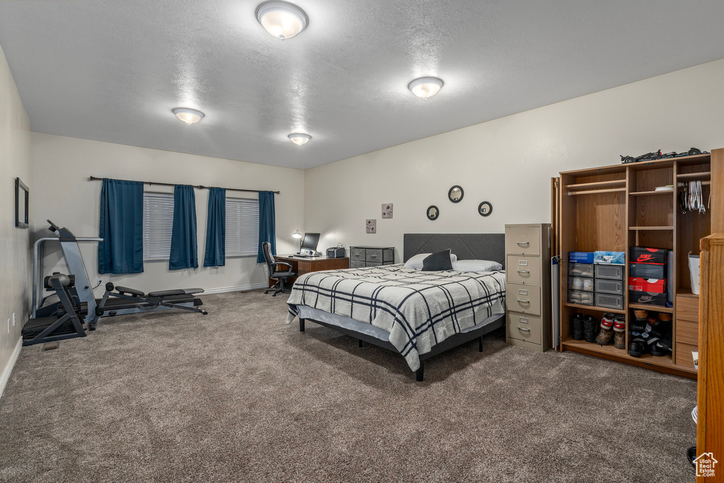 Carpeted bedroom featuring baseboards and a textured ceiling