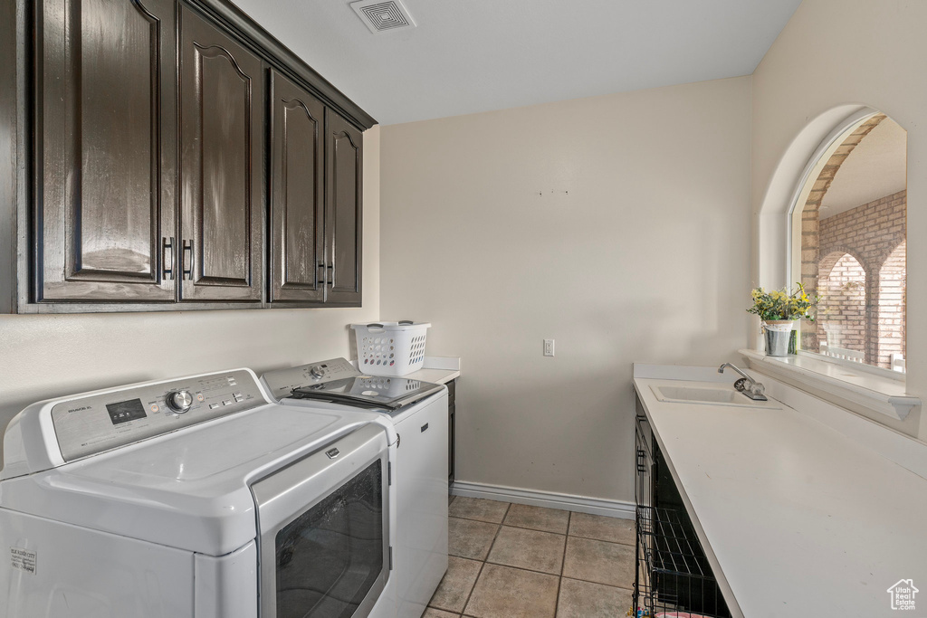 Laundry room with cabinet space, washing machine and dryer, baseboards, and light tile patterned floors
