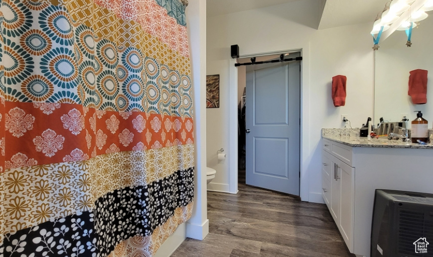 Bathroom featuring wood finished floors, toilet, vanity, a shower with shower curtain, and baseboards