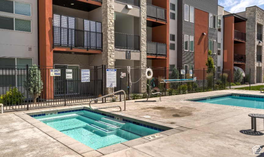 View of pool with fence and a hot tub