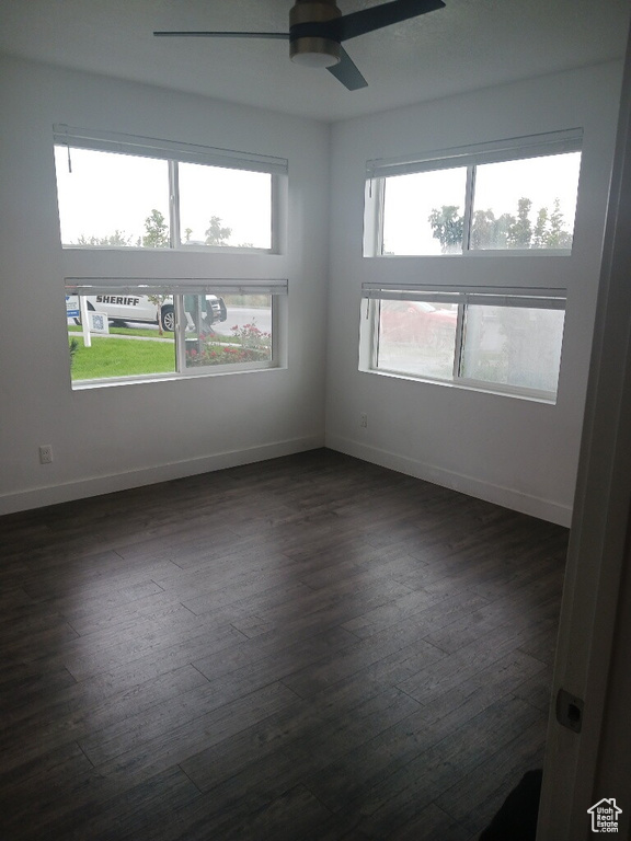 Spare room with dark wood-style floors, ceiling fan, and baseboards