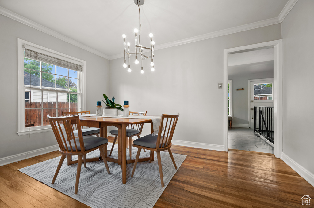 Dining space featuring ornamental molding, a chandelier, baseboards, and wood finished floors