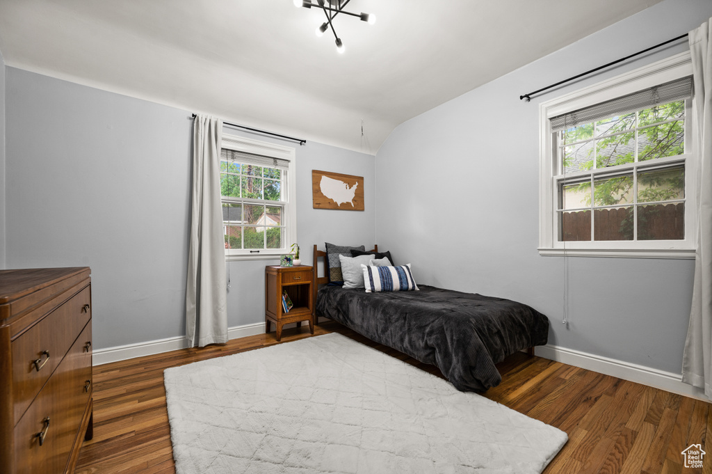 Bedroom with wood finished floors, baseboards, and vaulted ceiling