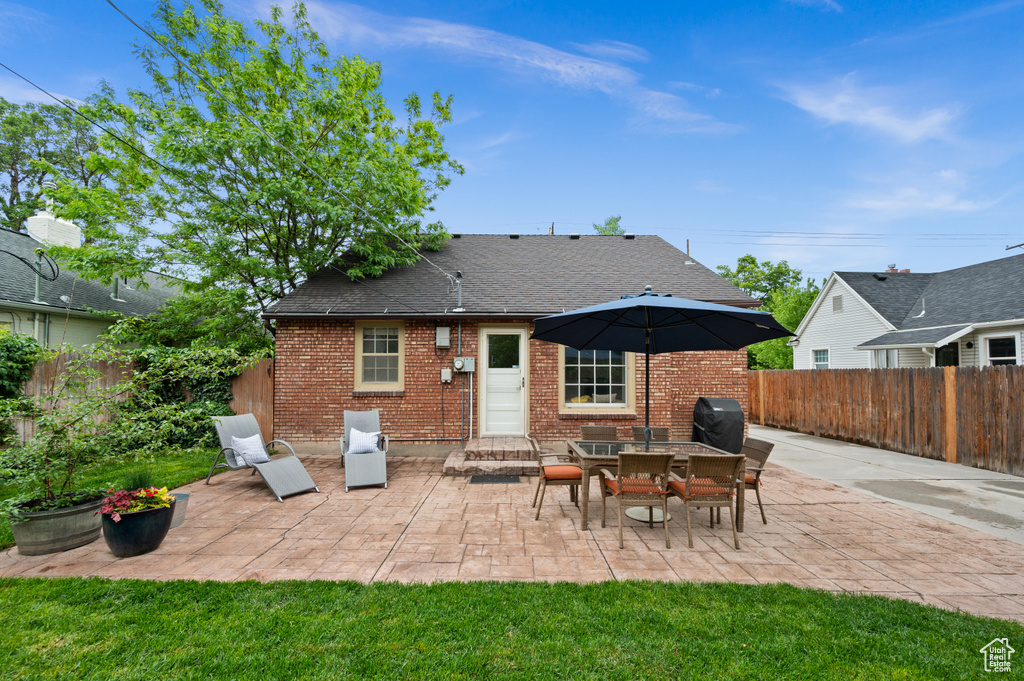 Back of house featuring brick siding, a fenced backyard, and a patio