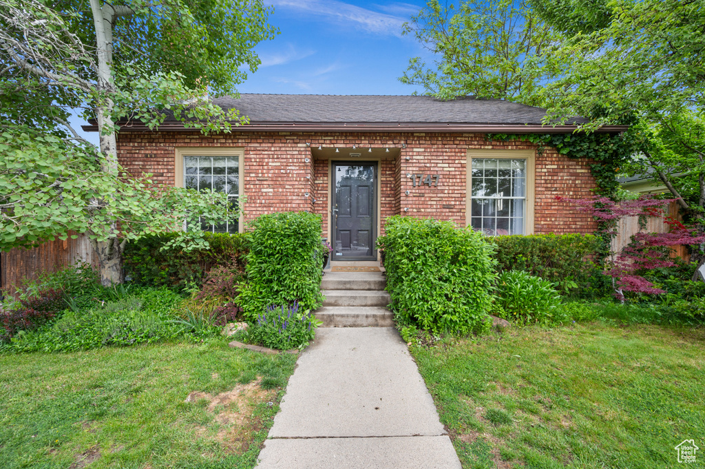 View of front facade featuring brick siding, a front lawn, and roof with shingles