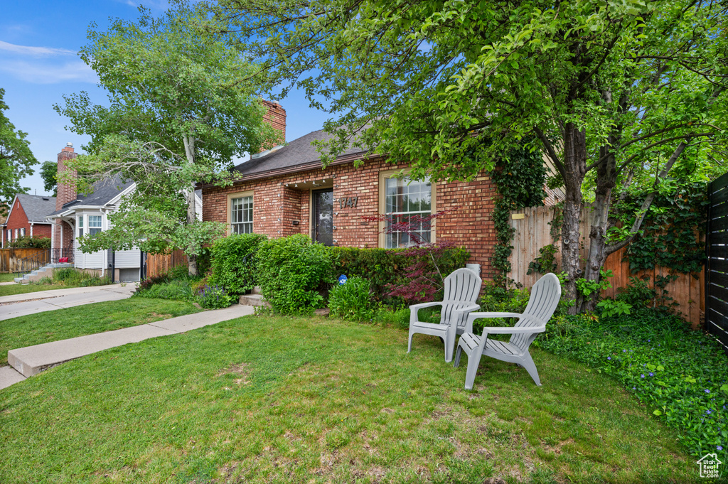 View of front facade featuring brick siding, driveway, and a chimney