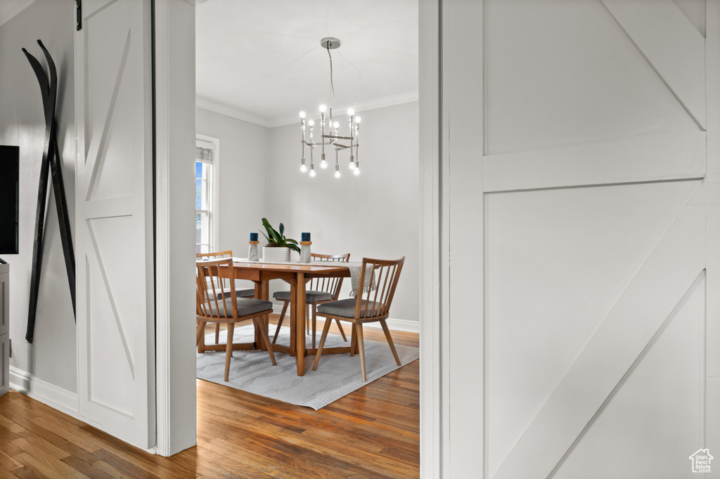 Dining area featuring wood finished floors, ornamental molding, baseboards, and a chandelier