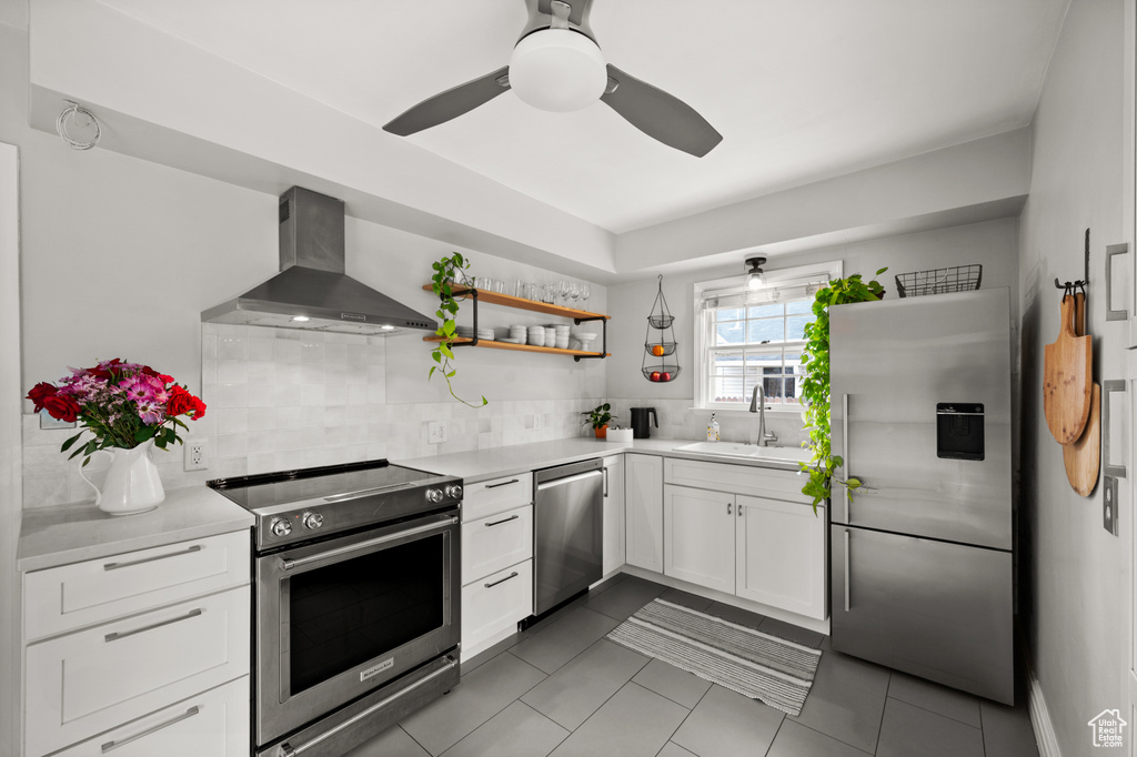 Kitchen with appliances with stainless steel finishes, wall chimney exhaust hood, a sink, white cabinets, and open shelves