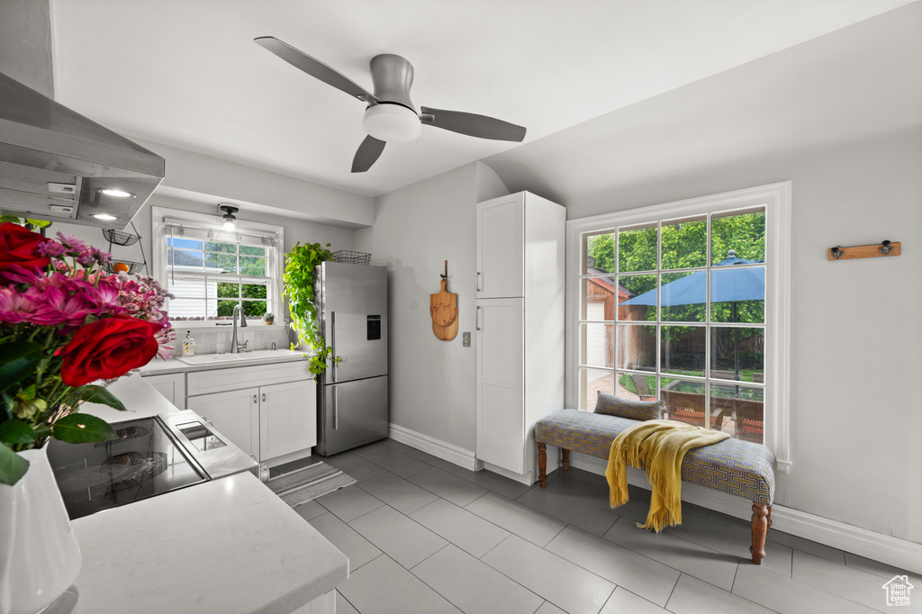 Kitchen featuring high end refrigerator, a sink, light countertops, white cabinetry, and baseboards