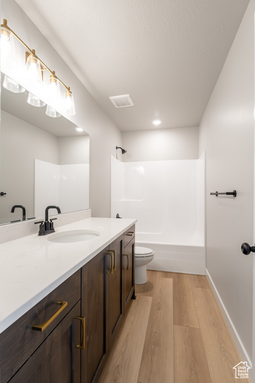Bathroom with wood finished floors, vanity, tub / shower combination, and recessed lighting