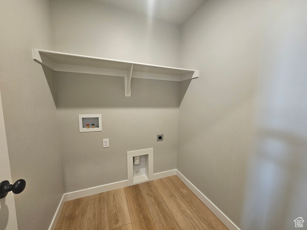 Washroom featuring electric dryer hookup, light wood-style flooring, baseboards, and washer hookup