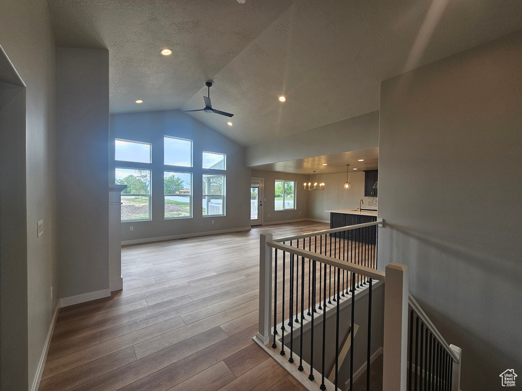 Hall featuring an upstairs landing, wood finished floors, a textured ceiling, baseboards, and a chandelier