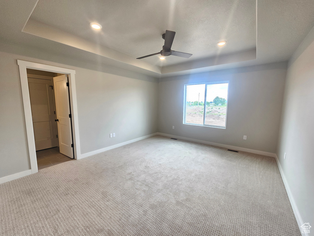 Spare room with a raised ceiling, carpet floors, a ceiling fan, baseboards, and a textured ceiling
