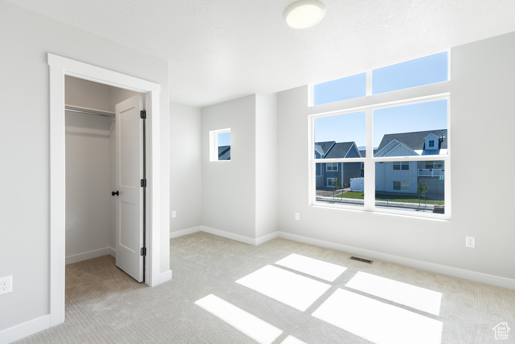 Unfurnished bedroom with carpet, a spacious closet, and a closet