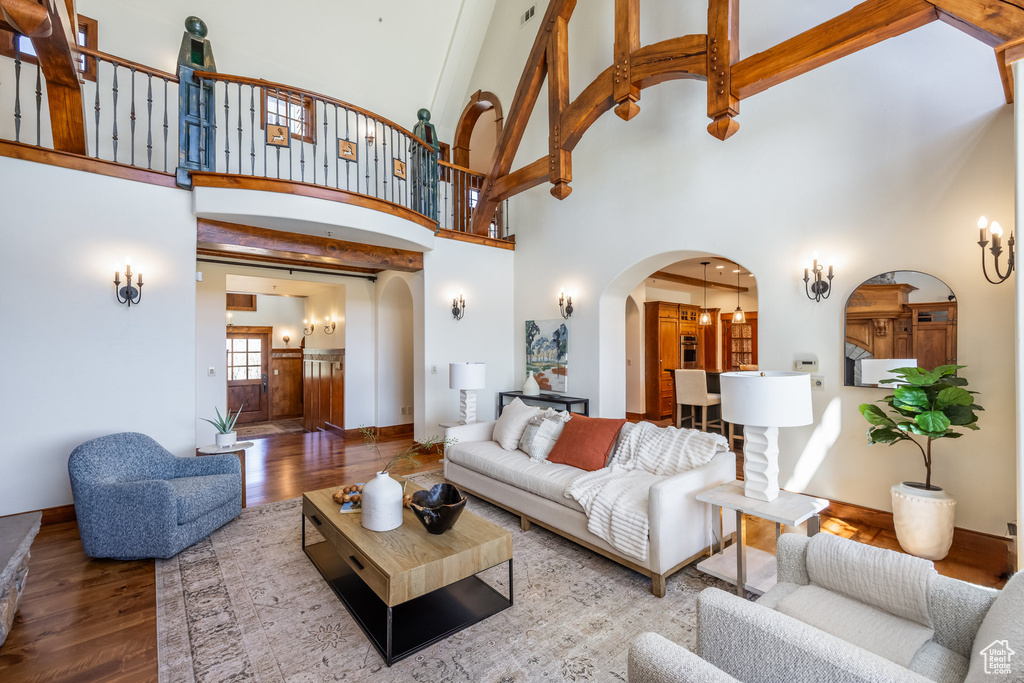 Living area featuring arched walkways, wood finished floors, a towering ceiling, and baseboards