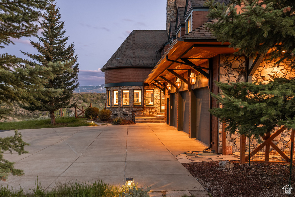 Property exterior at dusk featuring stone siding and a garage