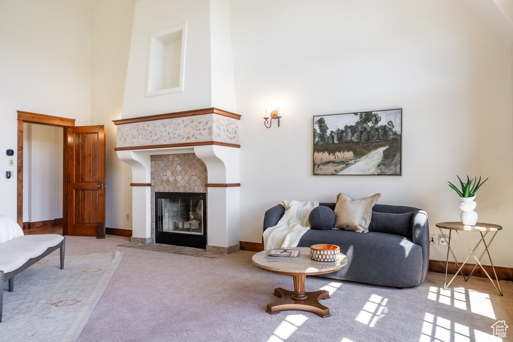 Carpeted living room with a towering ceiling, a fireplace, and baseboards