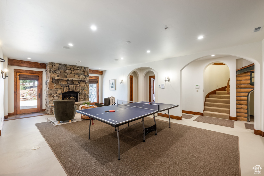 Recreation room with recessed lighting, arched walkways, a stone fireplace, and baseboards