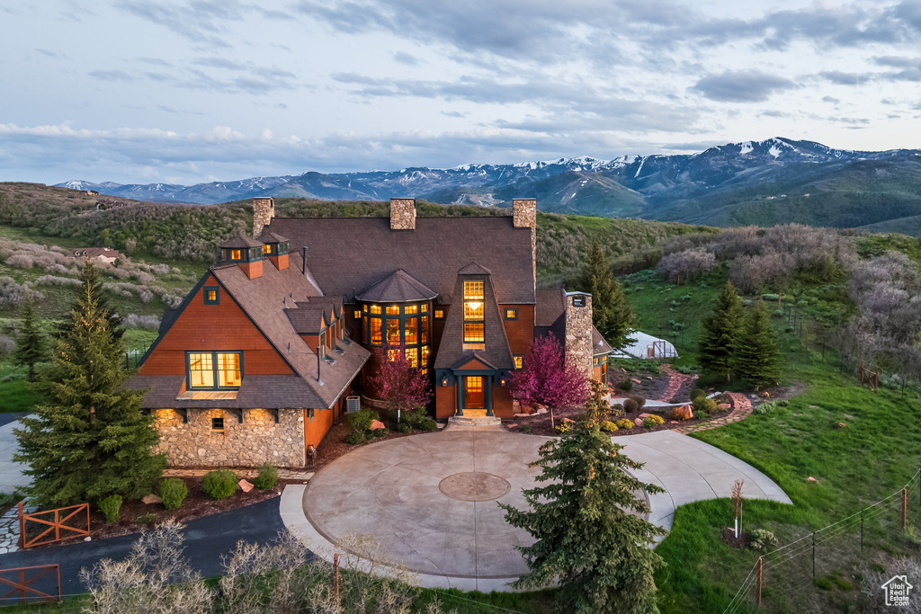 View of front of property featuring a chimney, curved driveway, and a mountain view
