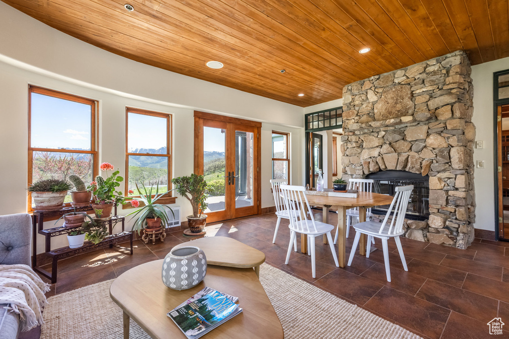 Tiled living room featuring wooden ceiling, french doors, a stone fireplace, recessed lighting, and baseboards