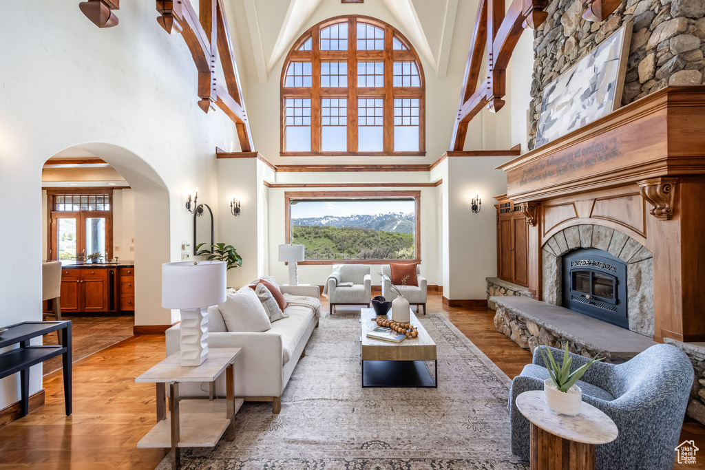 Living room featuring a high ceiling, light wood-style floors, plenty of natural light, arched walkways, and a fireplace