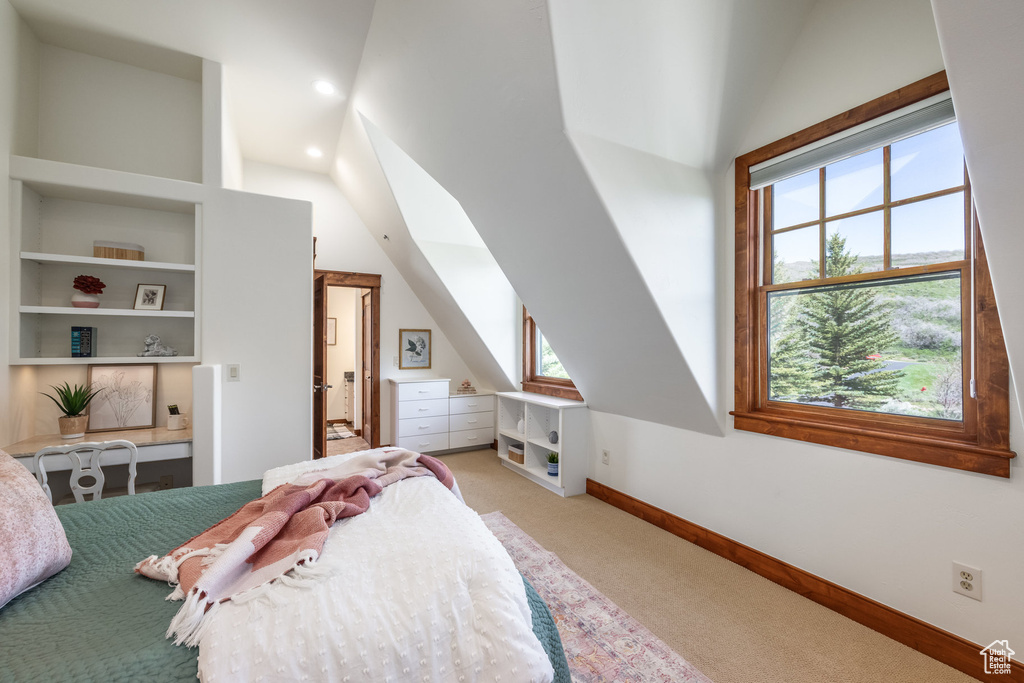 Carpeted bedroom with vaulted ceiling and baseboards