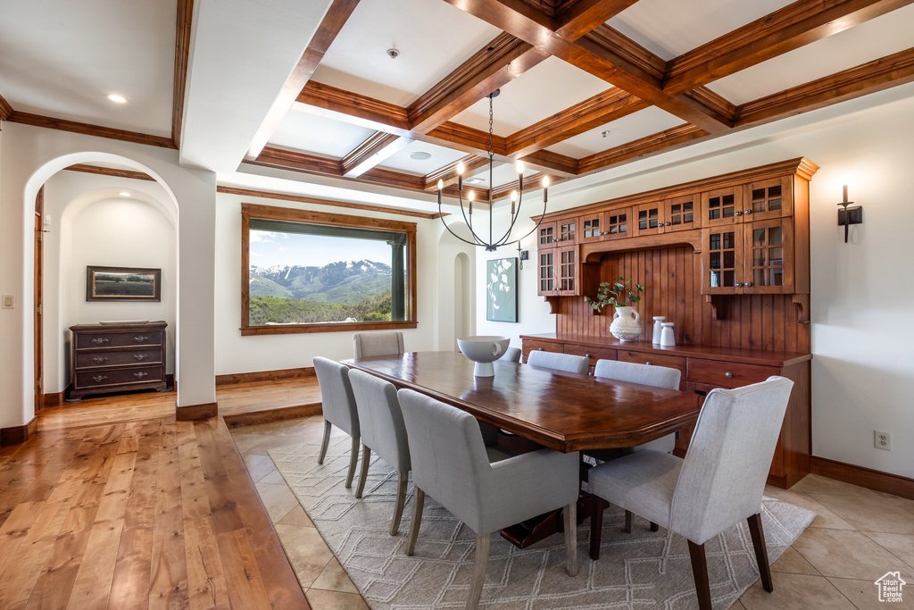 Dining space with arched walkways, beamed ceiling, baseboards, coffered ceiling, and ornamental molding
