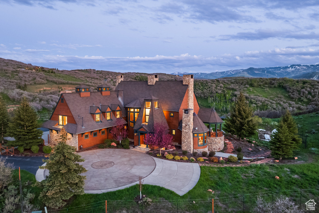 View of front facade with a chimney, curved driveway, and a mountain view