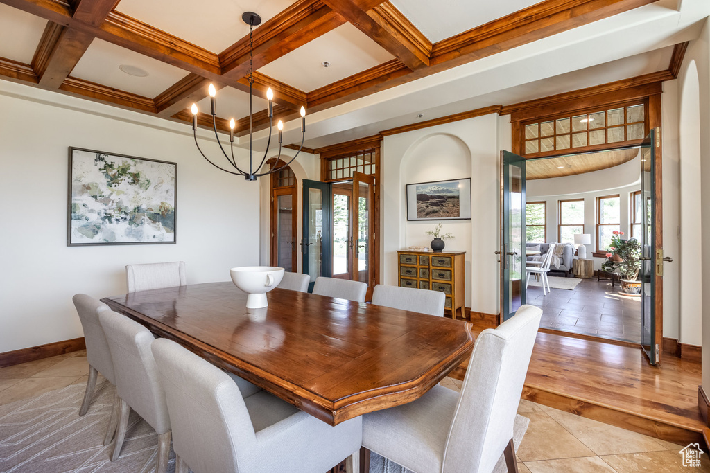 Dining room with beamed ceiling, baseboards, a chandelier, coffered ceiling, and french doors