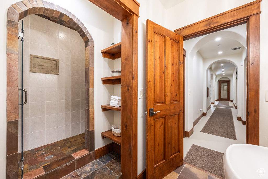 Bathroom featuring a stall shower, baseboards, and stone finish floors
