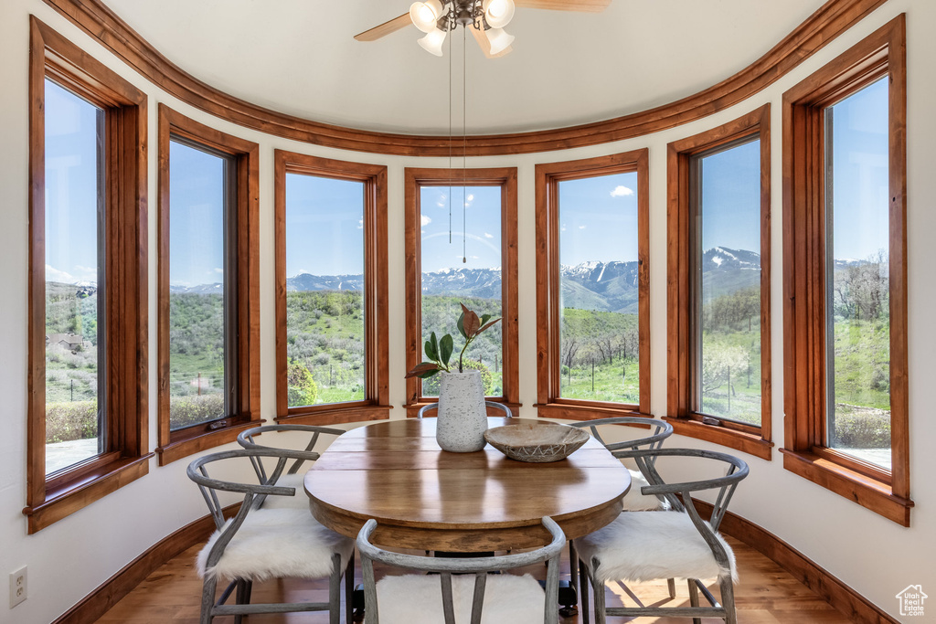 Dining space with baseboards, ceiling fan, a mountain view, and dark wood-style flooring