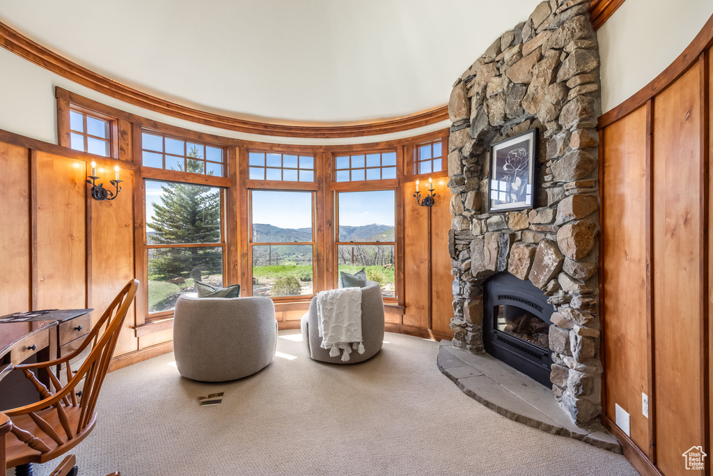 Living area with a mountain view, carpet flooring, a stone fireplace, and baseboards