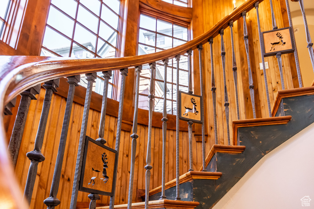 Stairs featuring a high ceiling and wooden walls