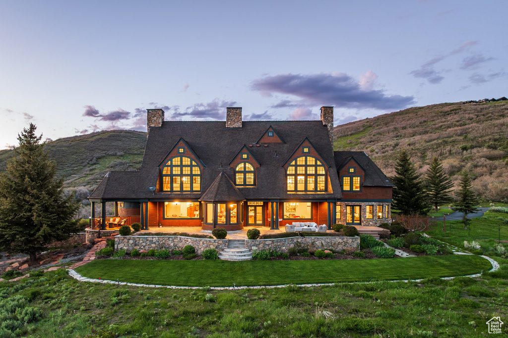 Back of property featuring a yard, a chimney, a mountain view, and covered porch