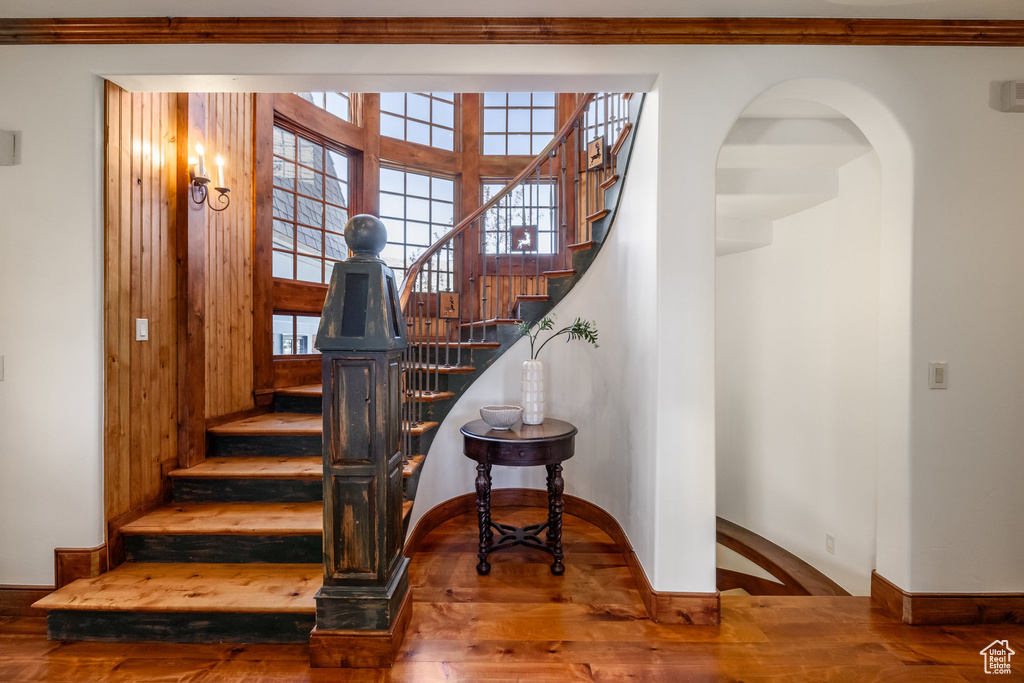 Stairway featuring wood finished floors, ornamental molding, and arched walkways