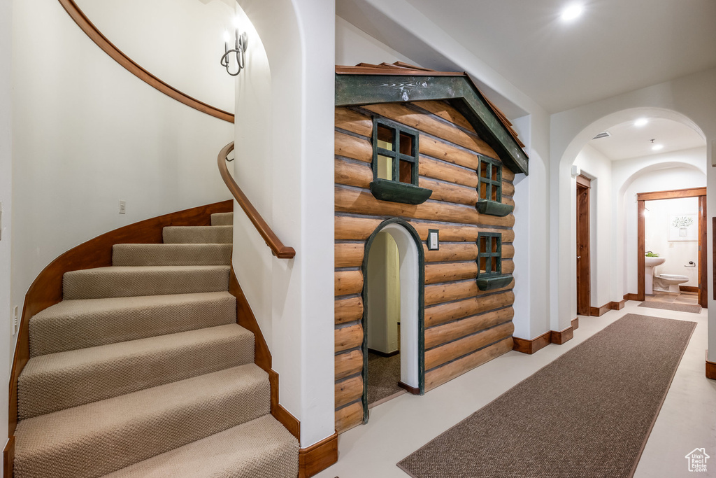 Stairway with rustic walls, arched walkways, and baseboards