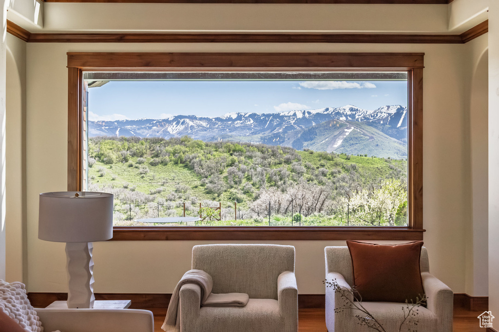 Living area with a mountain view, healthy amount of natural light, wood finished floors, and crown molding