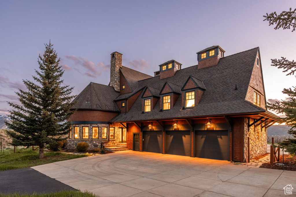 Shingle-style home featuring concrete driveway, stone siding, a garage, and a shingled roof