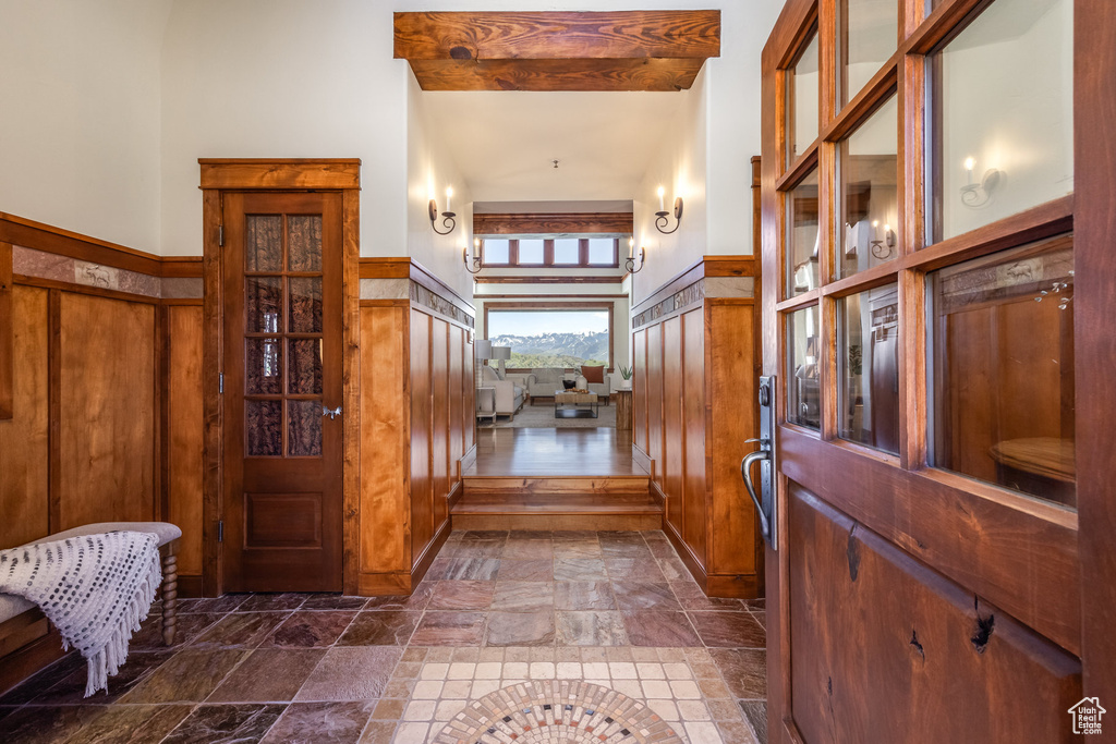 Entrance foyer with stone tile floors, wooden walls, and a high ceiling
