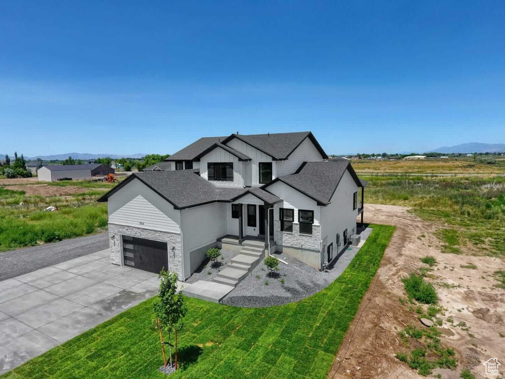 Modern farmhouse style home featuring driveway, stone siding, and a shingled roof