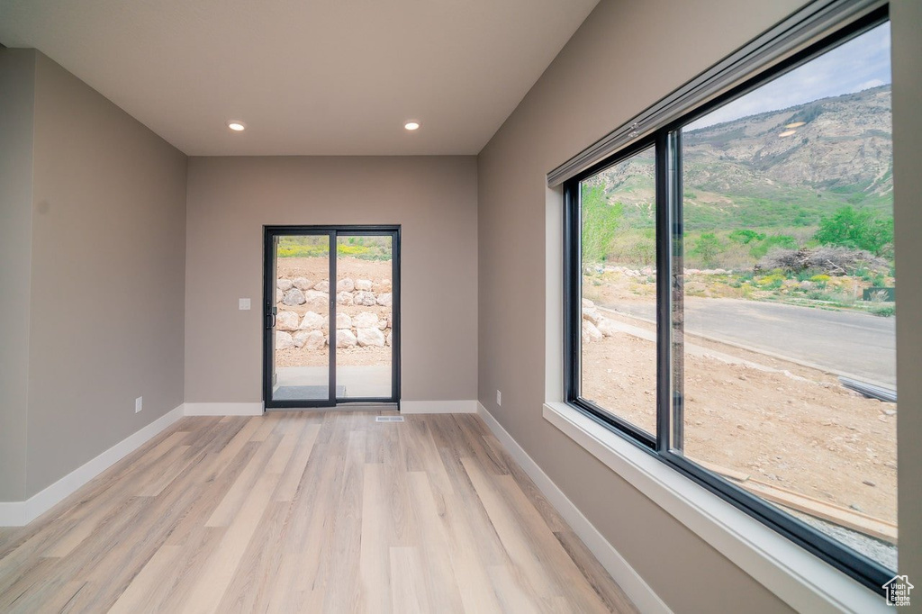 Spare room with healthy amount of natural light, light wood-style floors, recessed lighting, and baseboards