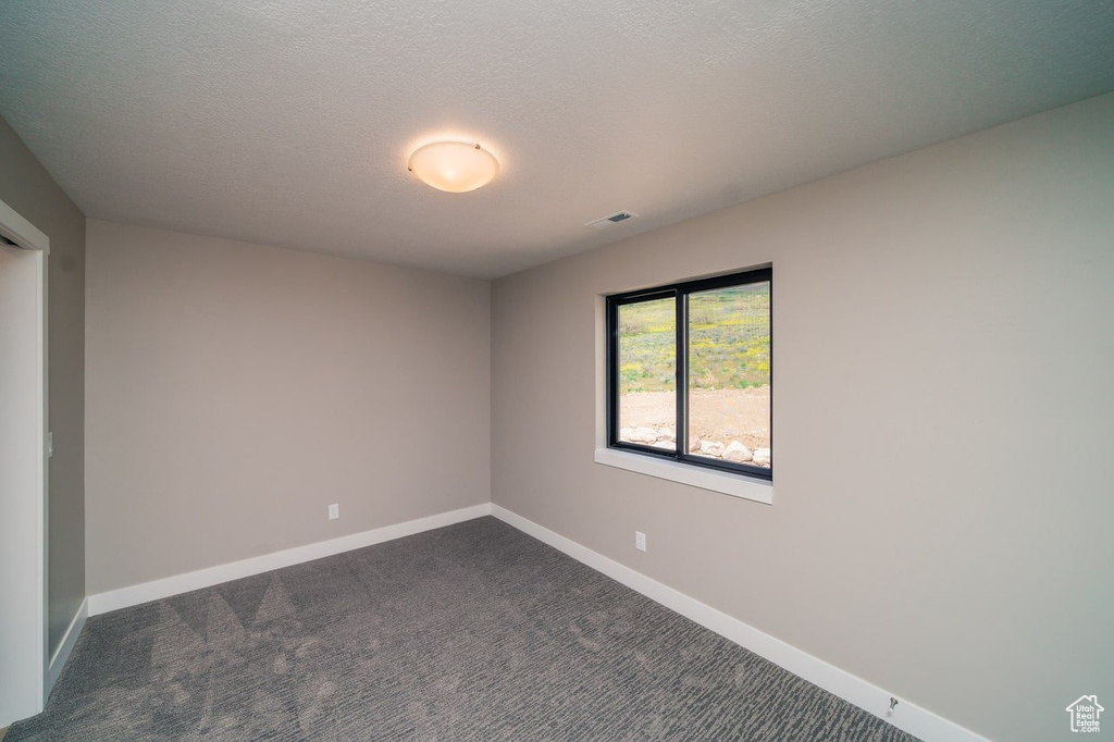 Empty room featuring dark carpet and baseboards