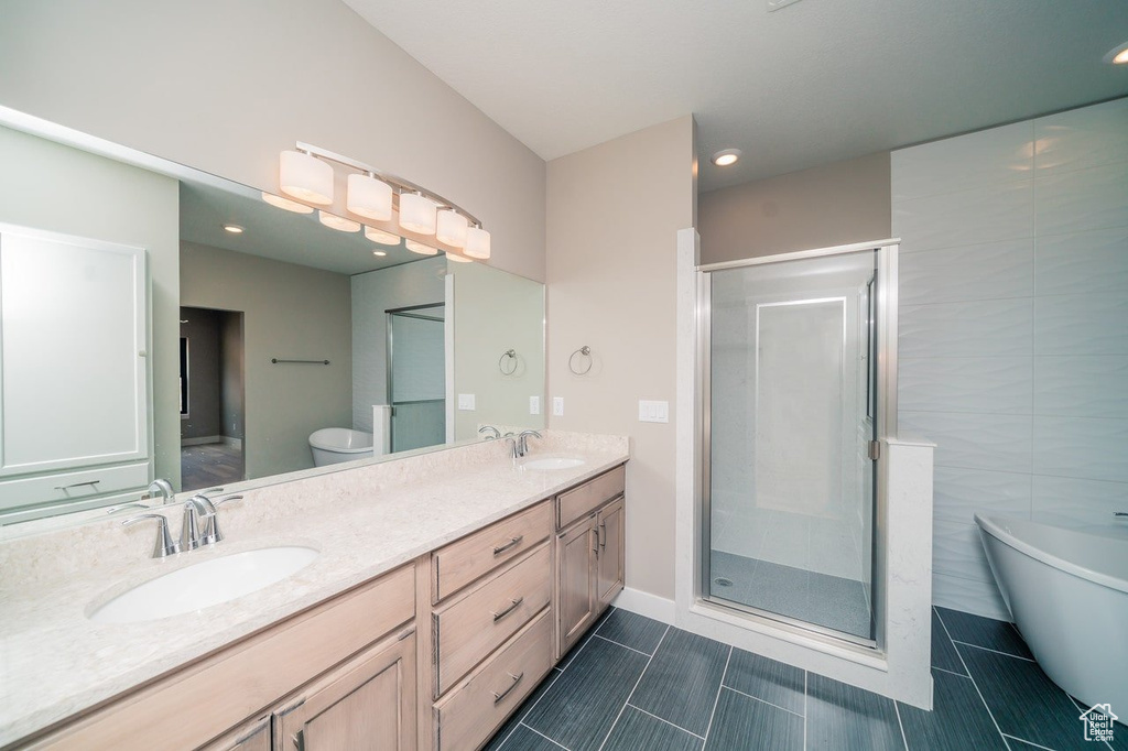 Bathroom with a stall shower, double vanity, a freestanding tub, tile patterned flooring, and recessed lighting