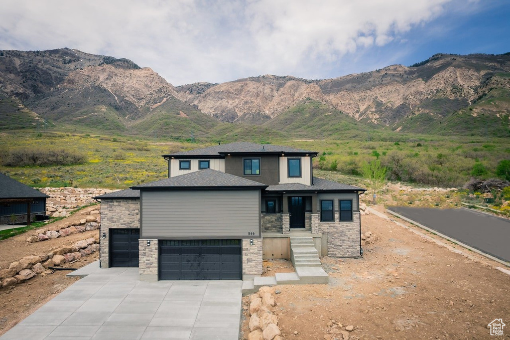 View of front of home with stone siding, driveway, and a mountain view