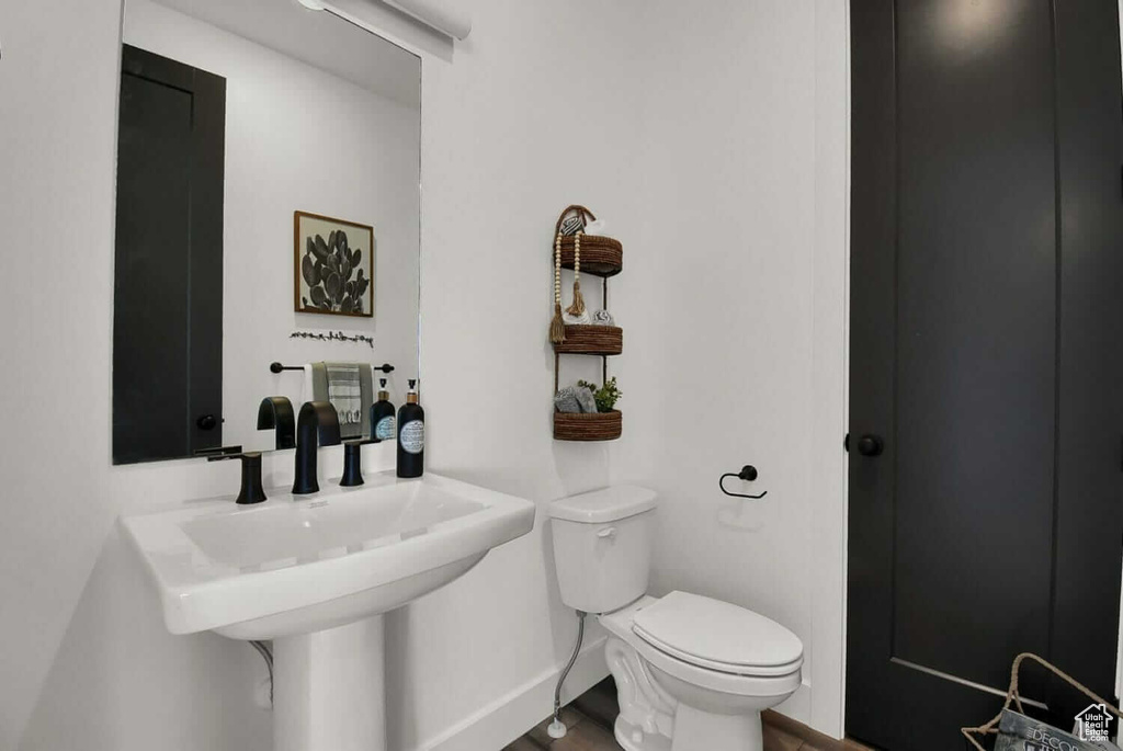 Half bathroom with toilet, baseboards, and a sink