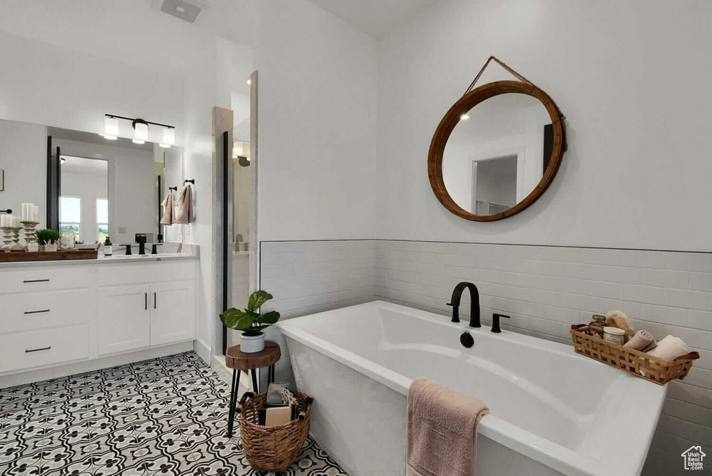 Full bathroom with a shower stall, a freestanding tub, vanity, and tile walls