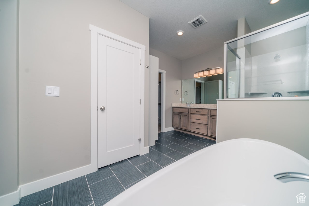 Bathroom featuring a stall shower, vanity, a freestanding tub, baseboards, and recessed lighting