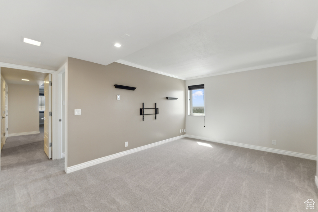 Spare room with light colored carpet, baseboards, and crown molding